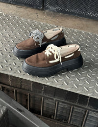 Par de Mocasines Apache Chunky Café de Animalista sobre escalera metálica, mostrando la opción de cordones intercambiables. Zapatos veganos de plataforma track y diseño local.