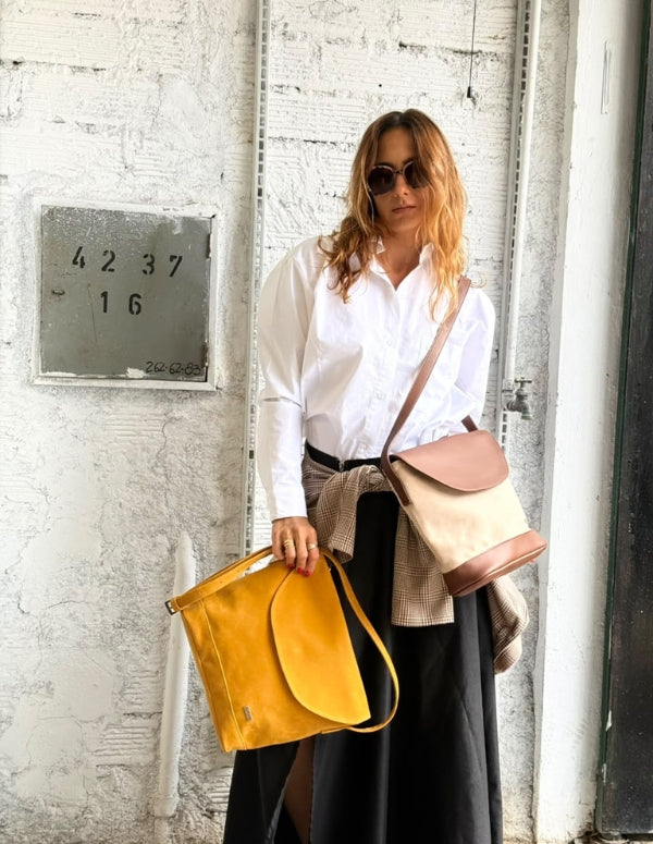 Mujer con look casual sosteniendo el Bolso Cylinder bicolor en tonos neutros de Animalista.