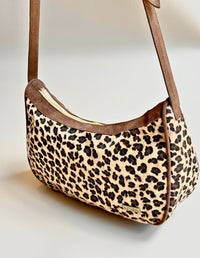 Vista lateral de cartera estilo hobo con estampado de leopardo y cargadera café. Fabricado sin materiales de origen animal.