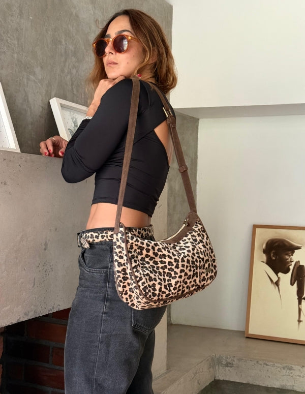 Mujer luciendo un bolso hobo café con estampado de leopardo. Cartera manos libres de moda ética.