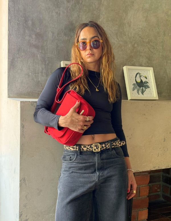 Mujer luciendo una cartera roja tipo manos libres. Accesorio versátil, elegante y libre de crueldad.