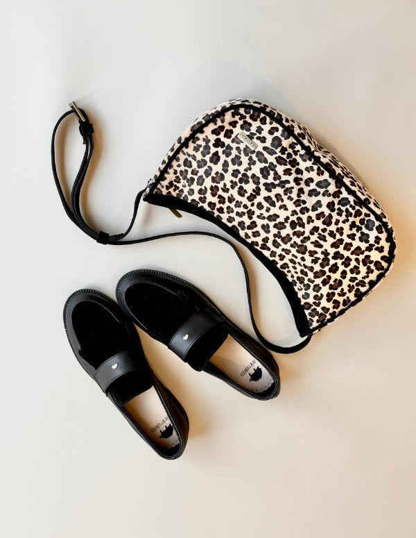 Look completo combinando mocasines clásicos negros y bolso manos libres de animal print leopardo.