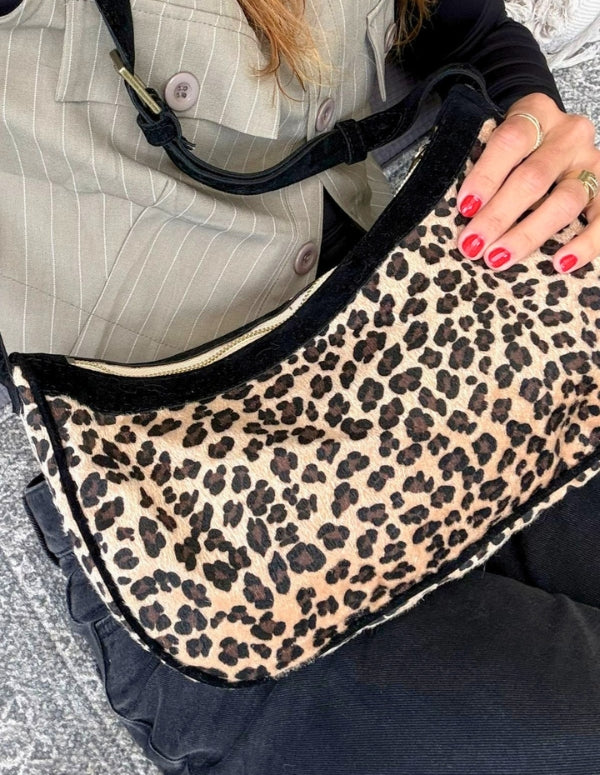 Detalle de cartera manos libres leopardo usada de medio lado. Bolso vegano fabricado con materiales alternativos premium.