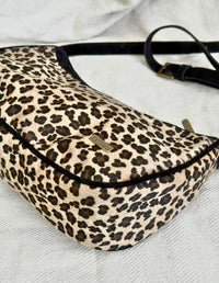 Vista superior de bolso cruzado con estampado de leopardo y correa negra. Accesorio versátil y consciente.