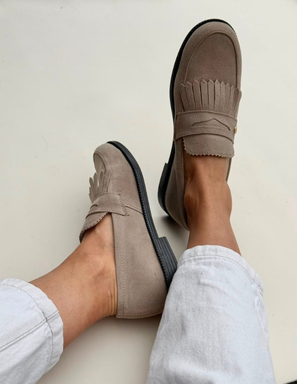 Mujer luciendo mocasines classic color arena con flecos frontales y suela negra. Zapatos de moda ética.