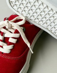Acercamiento a los tenis Slow Rojo mostrando el contraste de la textura roja con los ojales metálicos y los cordones blancos.