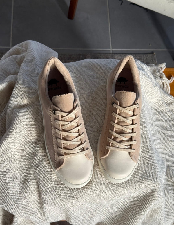 Par de tenis bajos para mujer en blanco y gamuza beige. Zapatos cómodos, versátiles y de moda consciente para el uso diario.