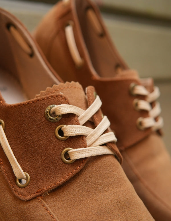 Primer plano en ángulo de zapatos mocasines apache latte mostrando los detalles de las costuras y cordones.