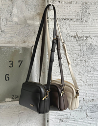Colección de bolsos tipo bandolera manos libres en colores negro, café y beige colgados de una pared   . Accesorios veganos Animalista.