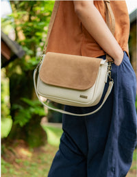 Mujer luciendo un bolso midi estilo bandolera color beige con tapa color latte cruzado sobre el cuerpo. Accesorio de moda consciente y vegana hecho en Colombia.