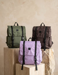 Colección de morrales utilitarios modelo Work Sport en colores verde oliva, lila y café oscuro sobre bases rústicas   . Mochilas veganas de Animalista.