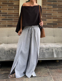 Mujer luciendo un pantalón boho gris claro de silueta amplia con aberturas frontales y top negro. Ropa cómoda de moda consciente hecha en Colombia.