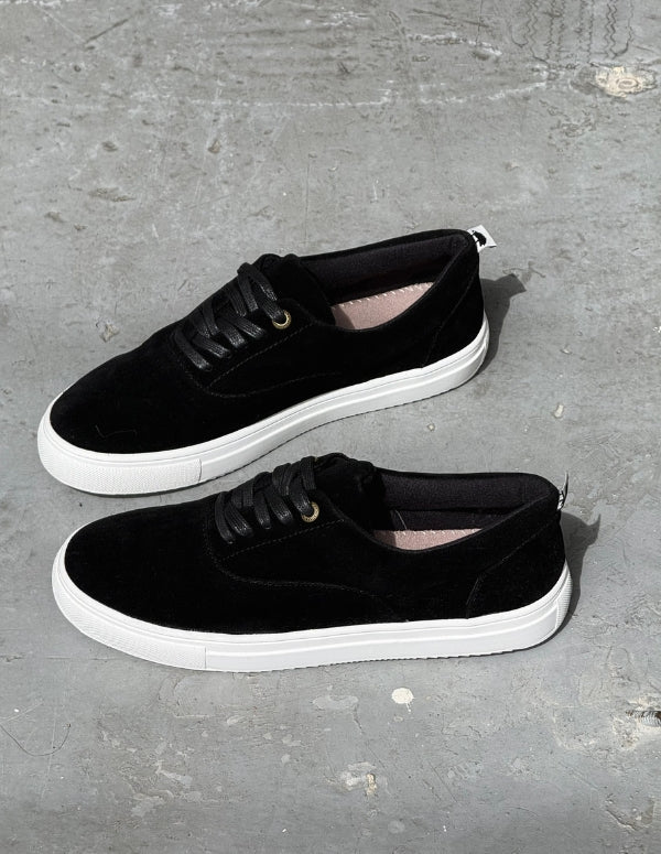 Par de zapatos pisahuevos negros de hombre sobre superficie de concreto. Diseño local colombiano.
