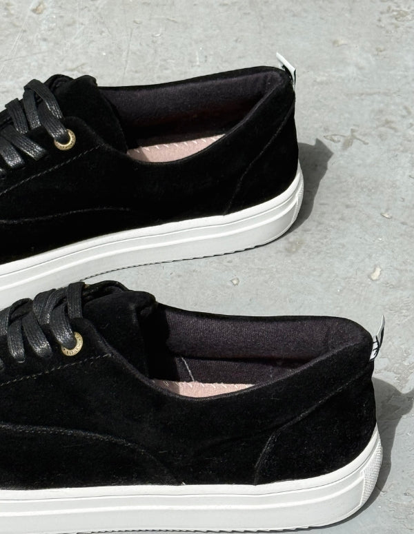 Perfil de zapatos casuales masculinos color negro destacando la suela plana blanca y las costuras.