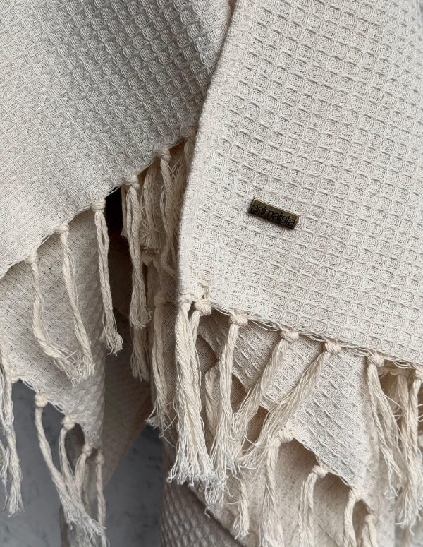 Acercamiento al tejido del poncho mostrando la textura del material, la suave caída y los flecos en el borde