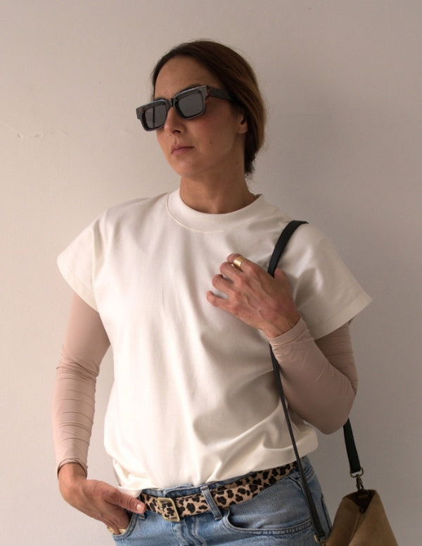 Mujer luciendo una camisa básica color beige de mangas estructuradas, combinada con jeans y gafas de sol. Ropa casual de moda ética hecha en Colombia.