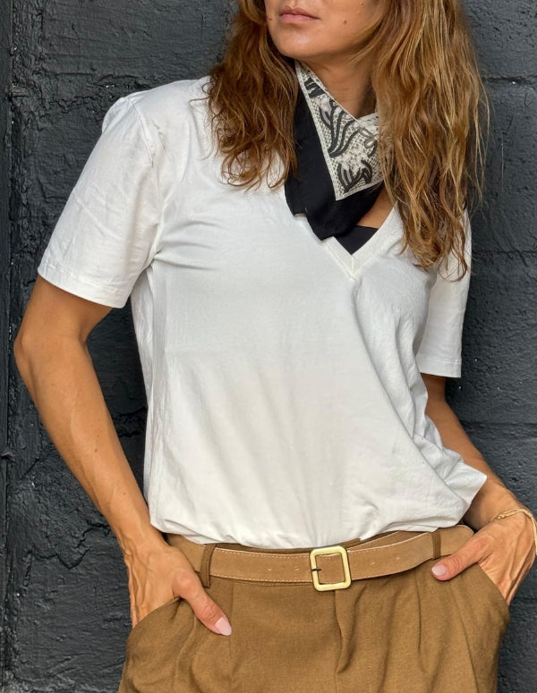 Mujer usando una camiseta blanca básica cuello en V llamada Signature T Shirt, combinada con pantalón café y pañoleta. Ropa esencial de moda ética hecha en Colombia.
