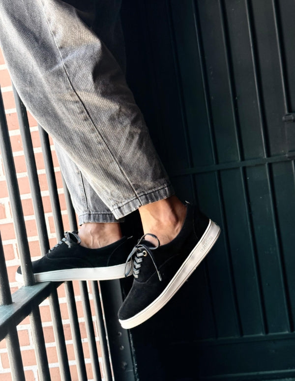 Par de tenis casuales estilo slow color negro con cordones y suela plana blanca para mujer. Calzado urbano de moda ética y vegana.