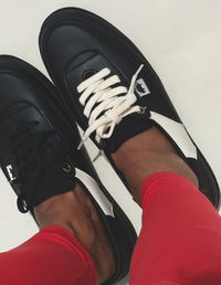 Mujer vistiendo un pantalón rojo vibrante y luciendo los Tenis Cool Negro de estilo retro de Animalista.